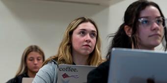 Three students with laptops in class
